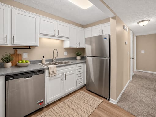 Virtually staged apartment kitchen with white cabinets and a stainless steel refrigerator at Arbours at Victoria Place in Prattville, AL