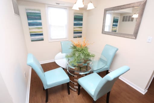 a small dining room with a glass table and blue chairs