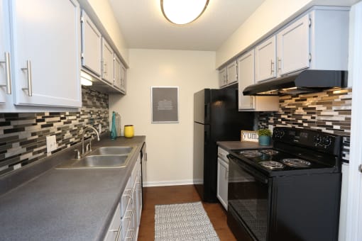 a kitchen with white cabinets and black appliances