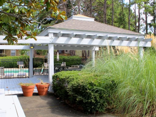 a white gazebo with plants in front of it