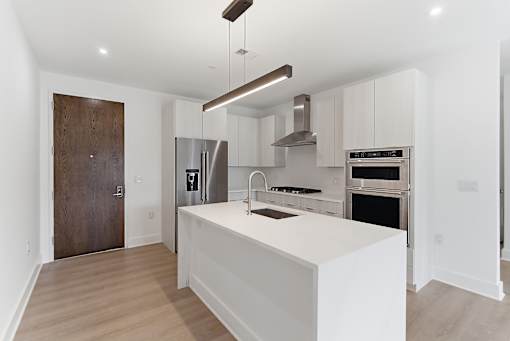 A modern kitchen with a white island and stainless steel appliances.