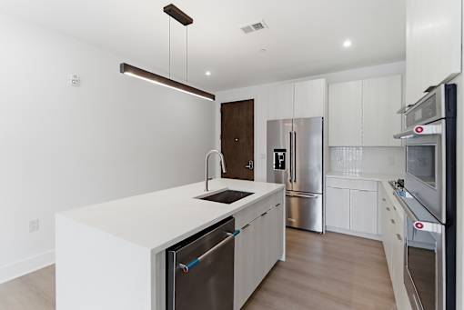 A modern kitchen with stainless steel appliances and white cabinetry.