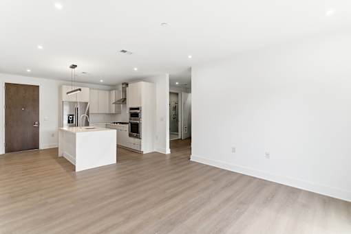 A modern kitchen with a white island and wooden floors.