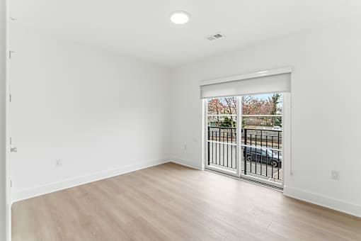 A room with a sliding glass door leading to a balcony.