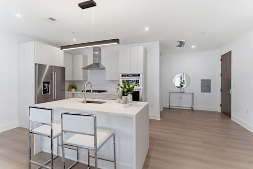 A modern kitchen with a center island and bar stools.