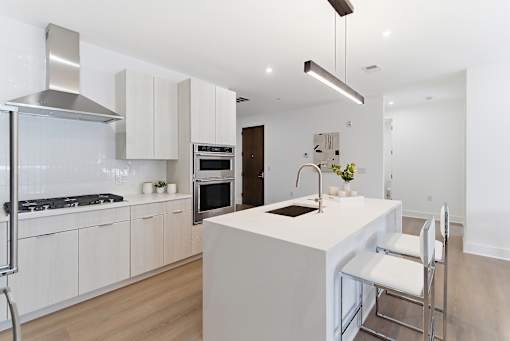 A modern kitchen with a white island and stainless steel appliances.