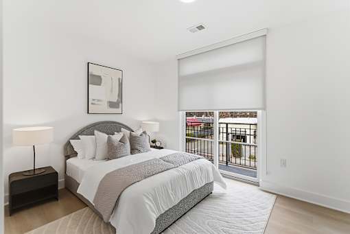 A bedroom with a large bed and a balcony.