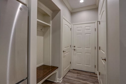 a walk in closet with white doors and a wooden bench