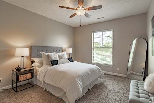 A bedroom with a large bed and a ceiling fan.