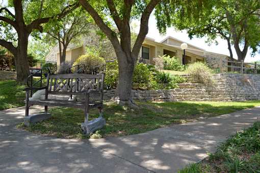 A playground with a swing set is located in front of a house.