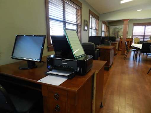 A room with a printer on a desk and a monitor.