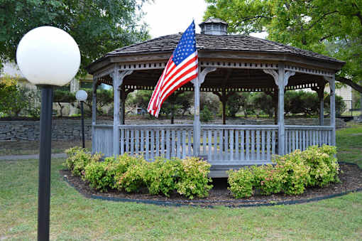 A gazebo with an American flag hanging from the roof.