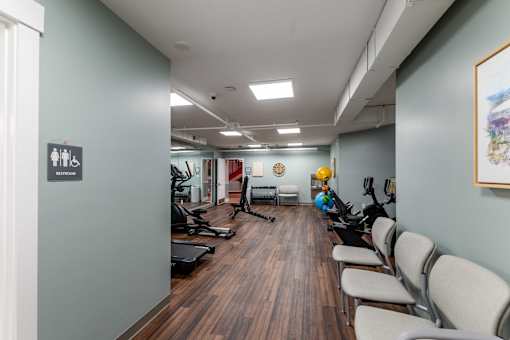 A gym with a row of chairs and exercise equipment.