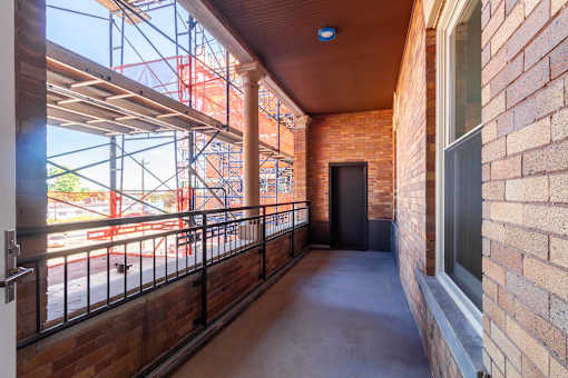 A balcony with a black railing and a brick wall.