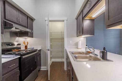 A kitchen with a stove, sink, and cabinets.