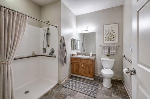 A bathroom with a white toilet, a white bathtub, a wooden cabinet, and a rug on the floor.