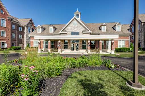 A building with a brick facade and a tower on top is surrounded by a garden.