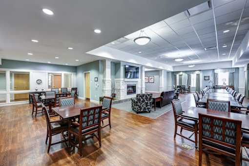 A large room with wooden floors and tables and chairs.