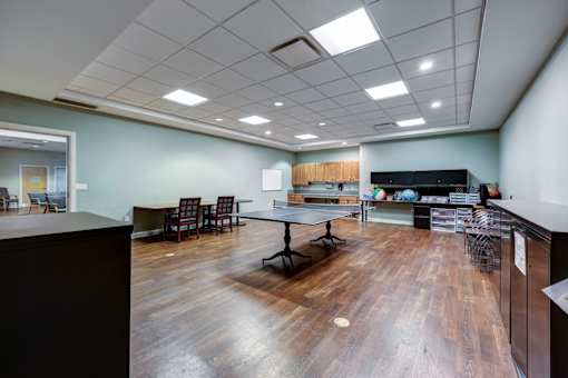 A room with wooden floors and a kitchen area with a refrigerator.