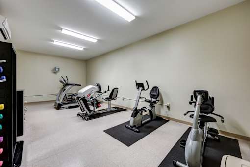A well-lit gym with a variety of exercise equipment.