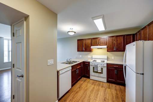 A kitchen with white appliances and wooden cabinets.