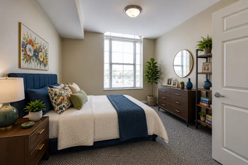 A bedroom with a bed, nightstand, and a window.