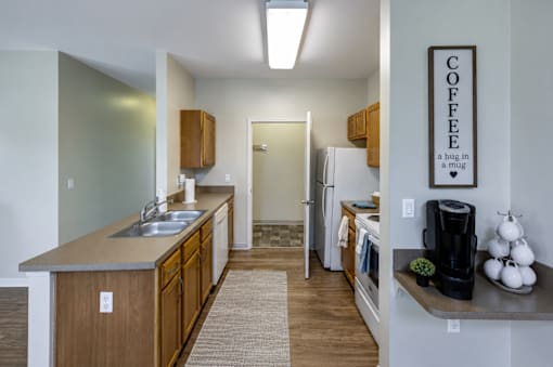 A kitchen with a refrigerator, sink, and a coffee sign on the wall.