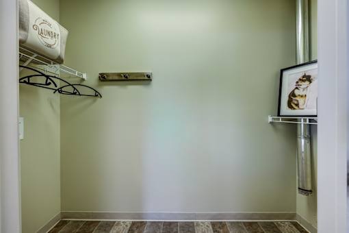 A laundry sign hangs on a wall next to a shelf and a picture frame.