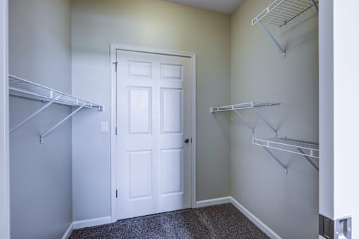 A white door is in the middle of a room with two shelves on either side.