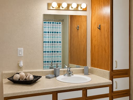 A bathroom with a sink, mirror, and a tray of bath bombs.
