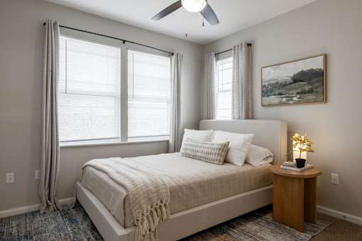 A bedroom with a bed, a ceiling fan, and a painting on the wall at Sunday Village