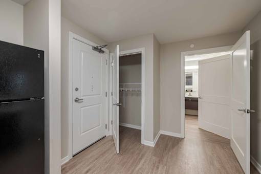 A black refrigerator is on the left in a kitchen with white doors.
