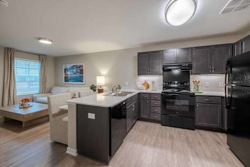 A modern kitchen with black cabinets and a white island.