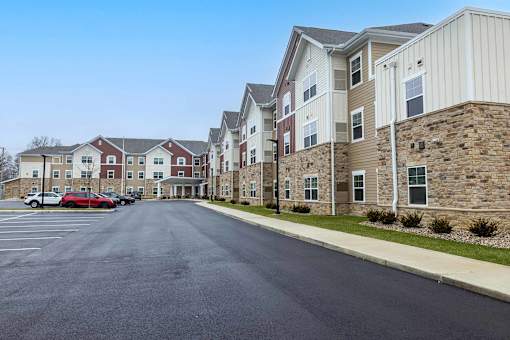 A parking lot in front of a row of apartment buildings.