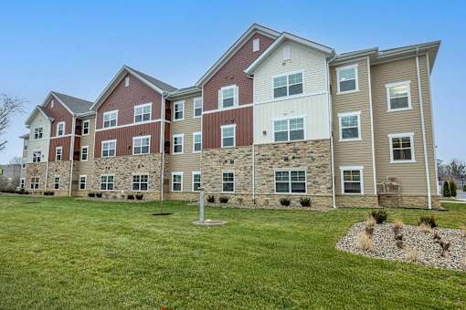 A large apartment complex with multiple buildings and a grassy front yard.