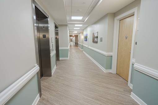 A long hallway with a door on the right and a wall with pictures on the left.