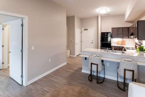 A kitchen with a white counter and brown chairs.
