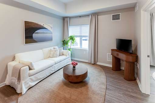 A living room with a white couch, a coffee table, and a painting on the wall.