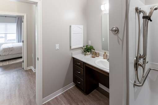 A bathroom with a sink, mirror, and shower.