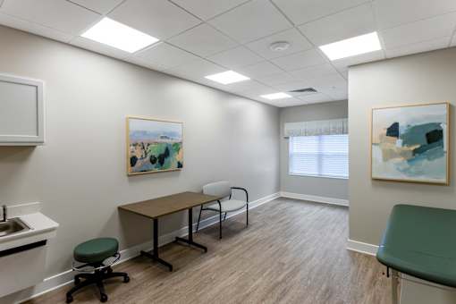 A room with a desk, chair, and two paintings on the wall.