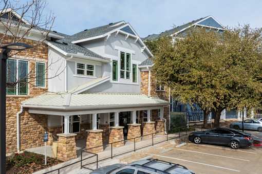 A carport is attached to a house with a stone wall at Sunday Village in Austin, TX