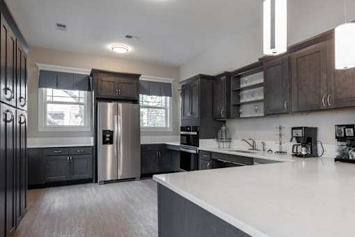 A modern kitchen with dark wood cabinets and a white countertop at Sunday Village