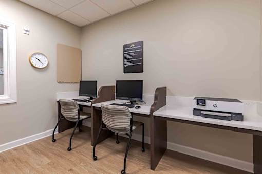 A room with a desk, chairs, and a clock on the wall.