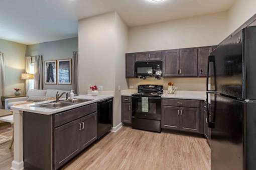 A kitchen with black appliances and brown cabinets.