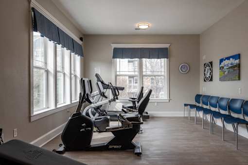 A gym with a row of exercise chairs and a treadmill at Sunday Village Apartments