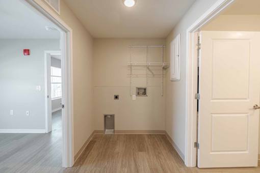 A white door is open to a room with a wood floor and white walls.