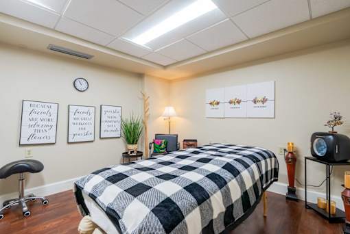 A massage table covered with a checkered heated blanket and a wall clock.