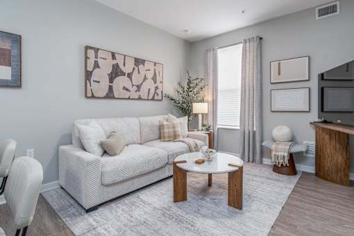 A living room with a white couch, a coffee table, and a painting on the wall.