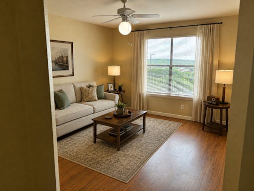 A living room with a couch, a coffee table, and a ceiling fan.