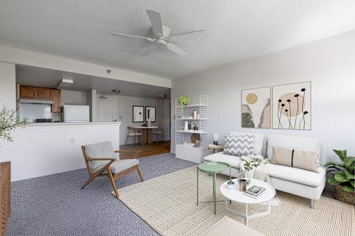 A living room with a white couch, a chair, a coffee table, and a ceiling fan.